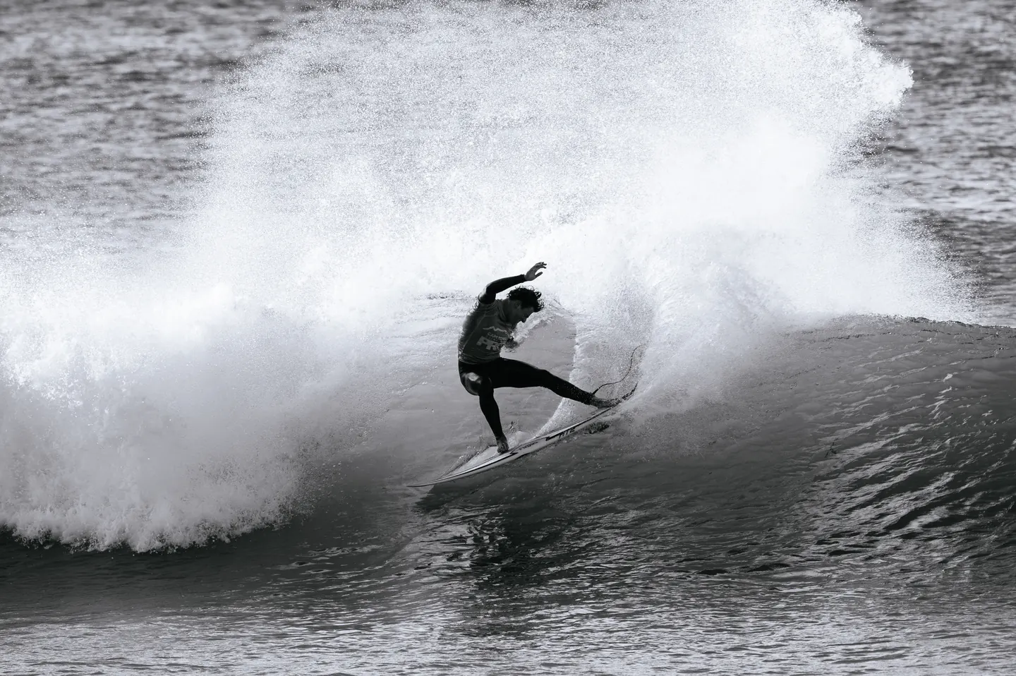 Close on Levi's board and back foot as he sets the rail, spray fanning off the tail.